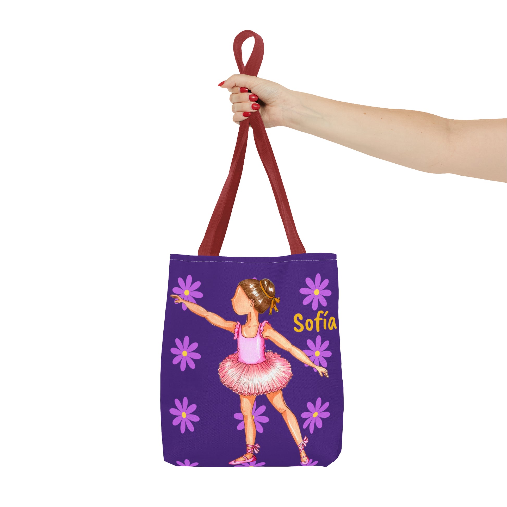a hand holding a purple tote bag with a picture of a ballerina