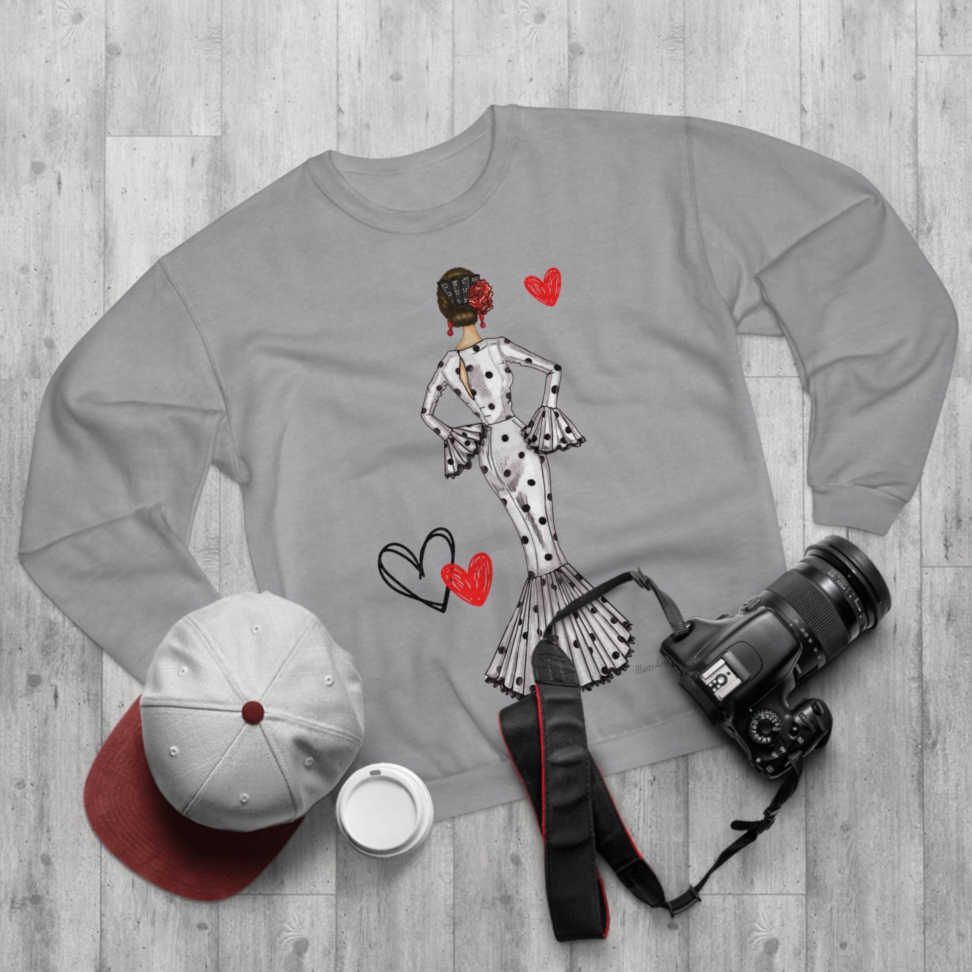 a sweater, hat, camera, and other items laid out on a wooden floor