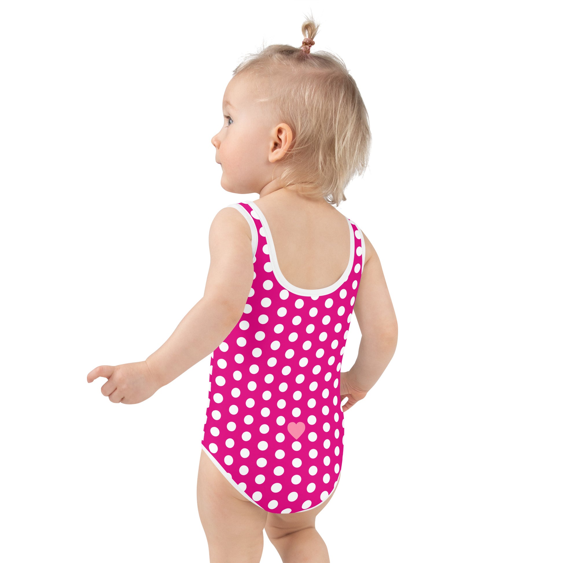 a little girl in a pink and white polka dot swimsuit
