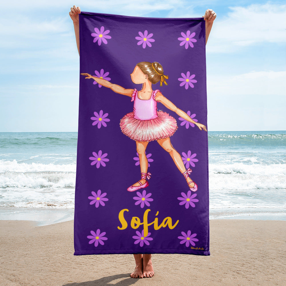 a little girl holding a purple towel with a picture of a ballerina on it