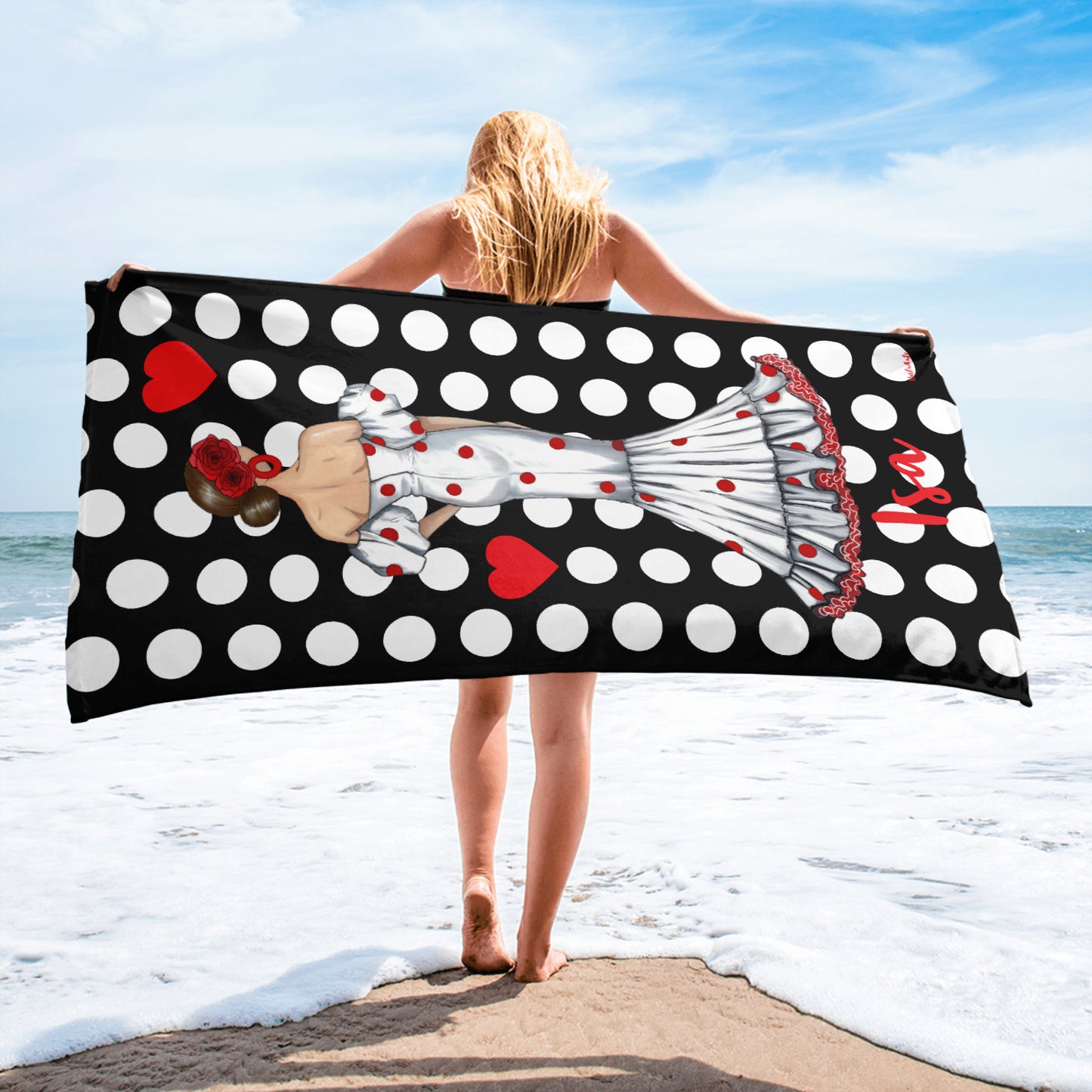 a woman standing on the beach holding a polka dot towel