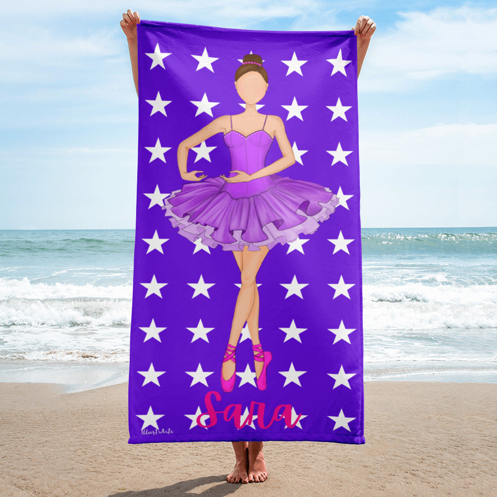 a woman standing on a beach holding a purple towel